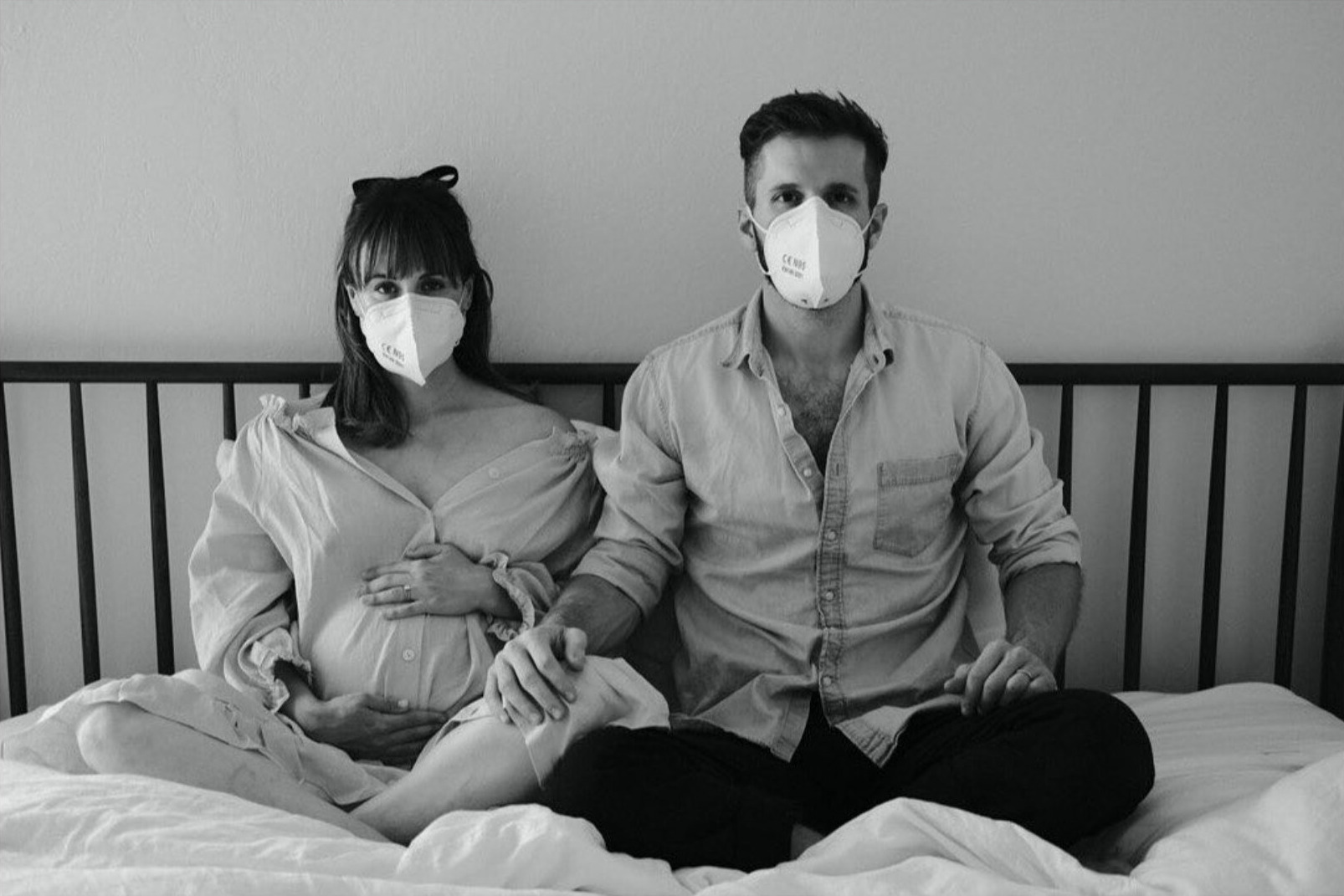 Black and white portrait of an expectant couple wearing masks