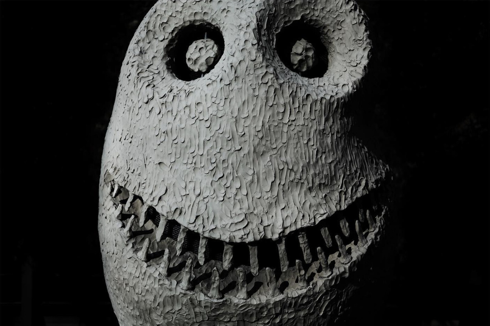 Black and white close-up of a smiling sculpted face